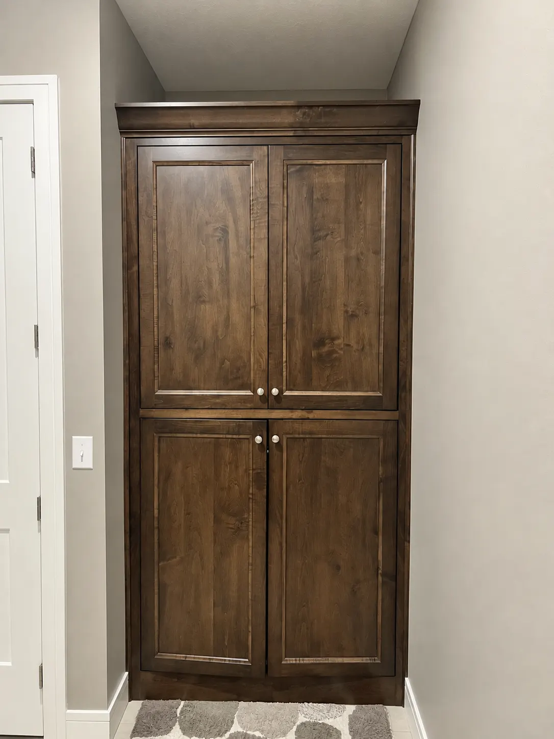Stained wood corner cabinet with four paneled doors