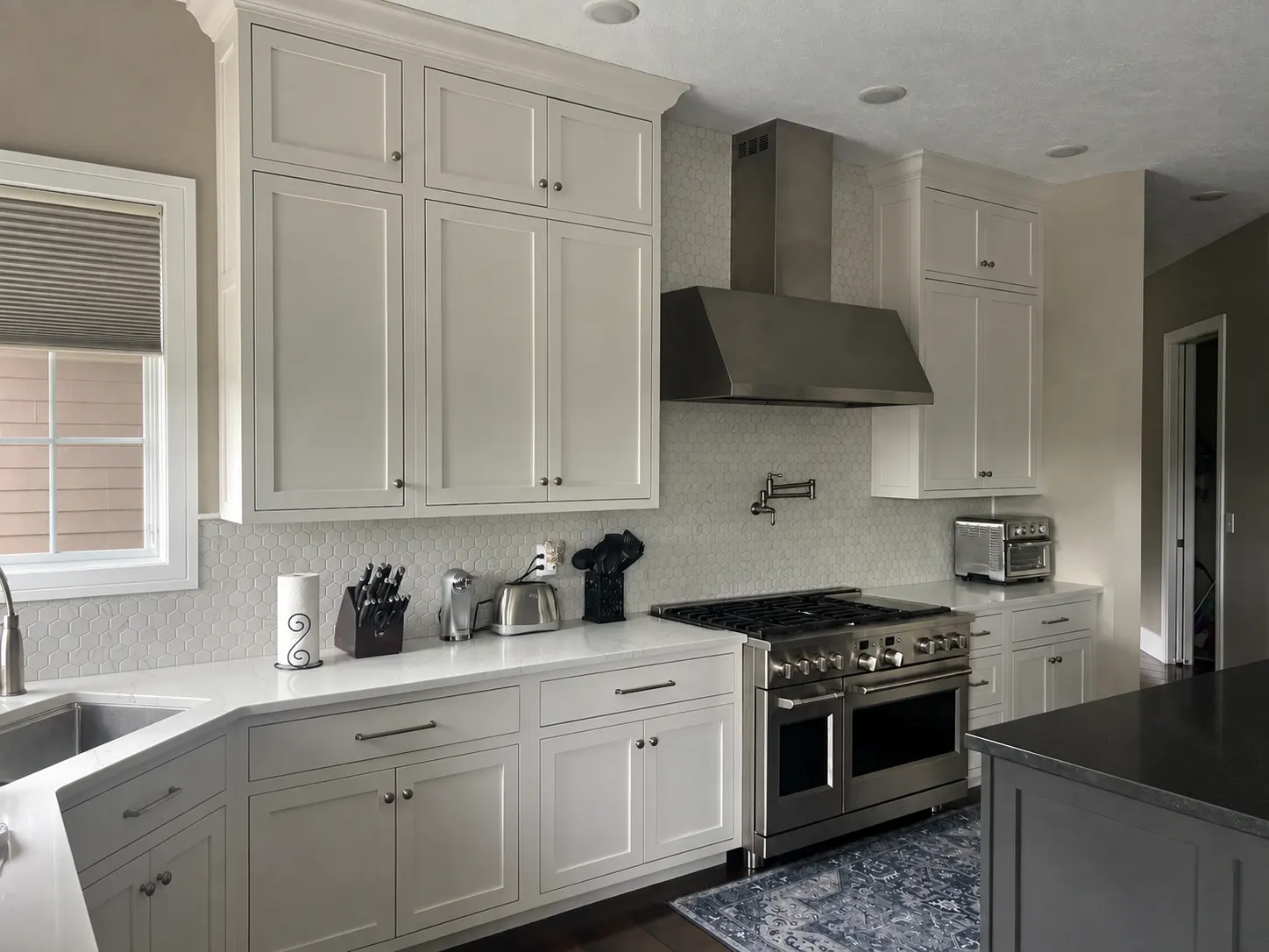 White custom kitchen with stainless range and marble-look counters
