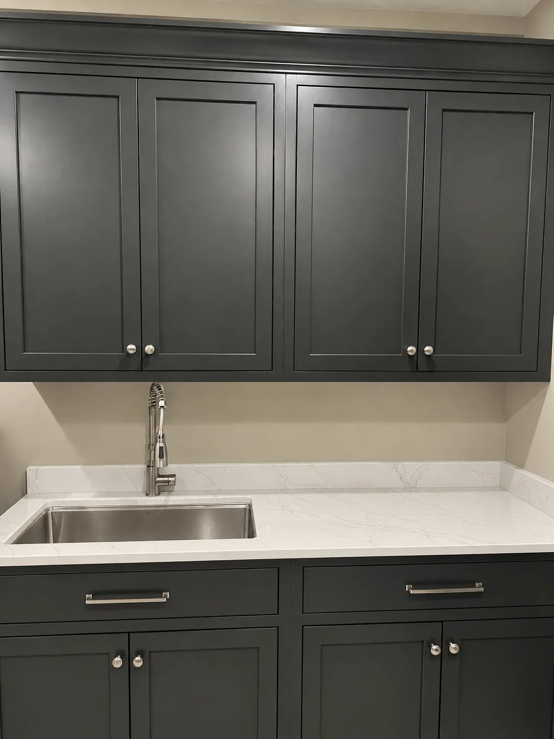 Dark laundry-room cabinets with a marble-look counter and sink