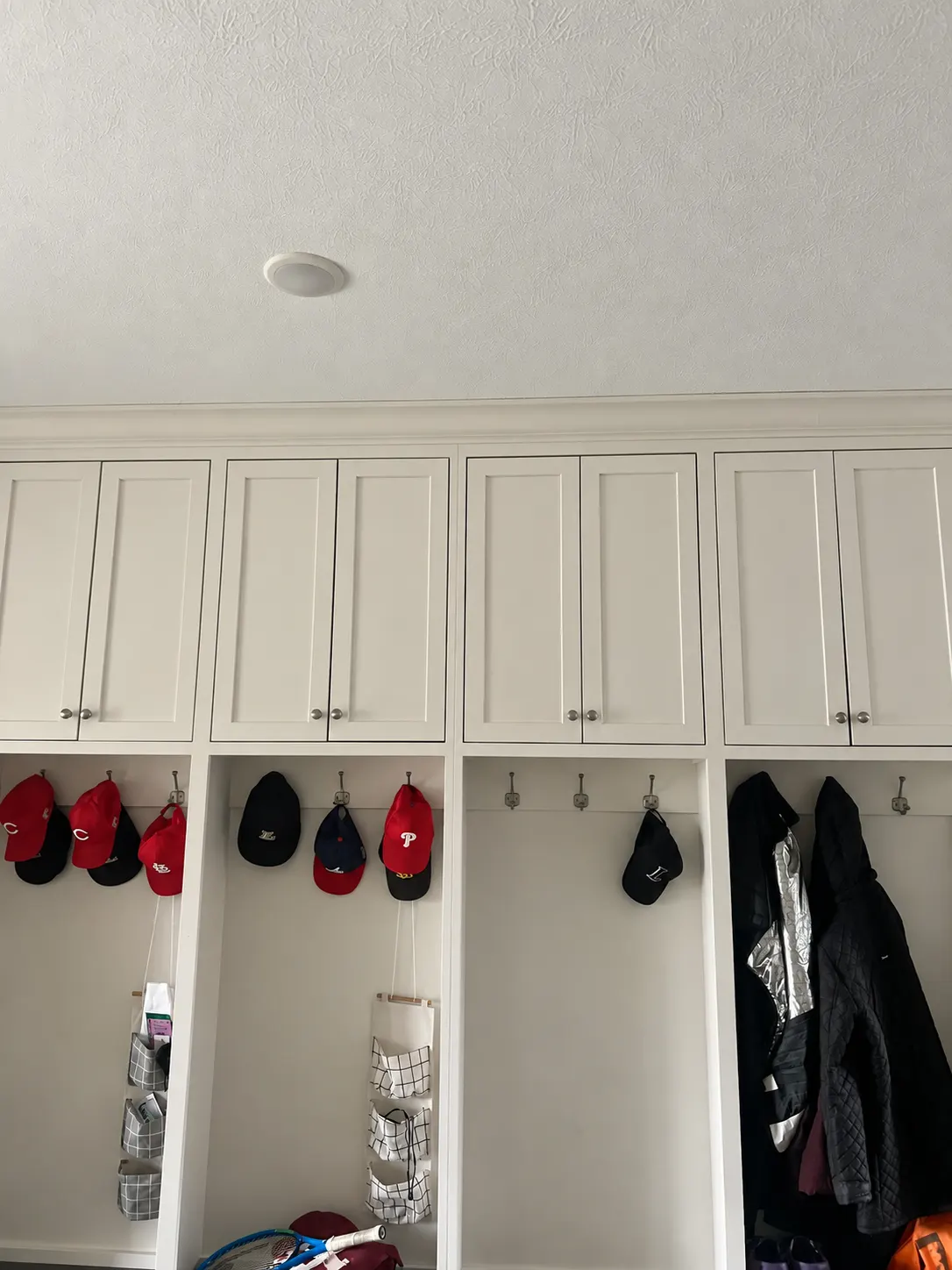 Painted mudroom cubbies with hooks and upper cabinets